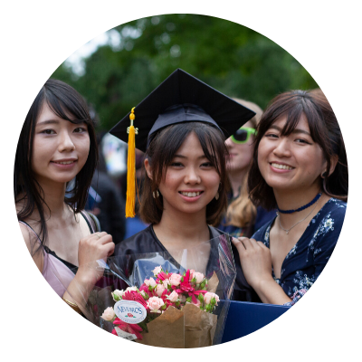 a student in cap & gown with their friends
